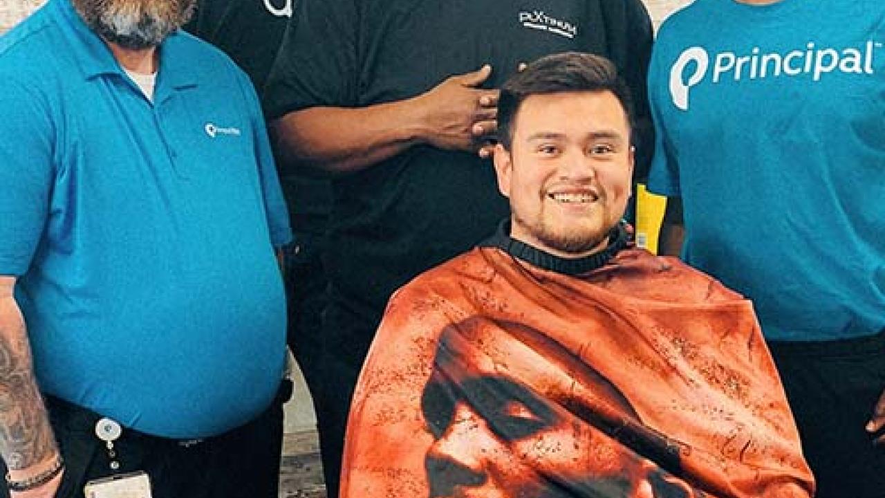 Jonas Cutler seated in a barber chair with three men standing behind him.