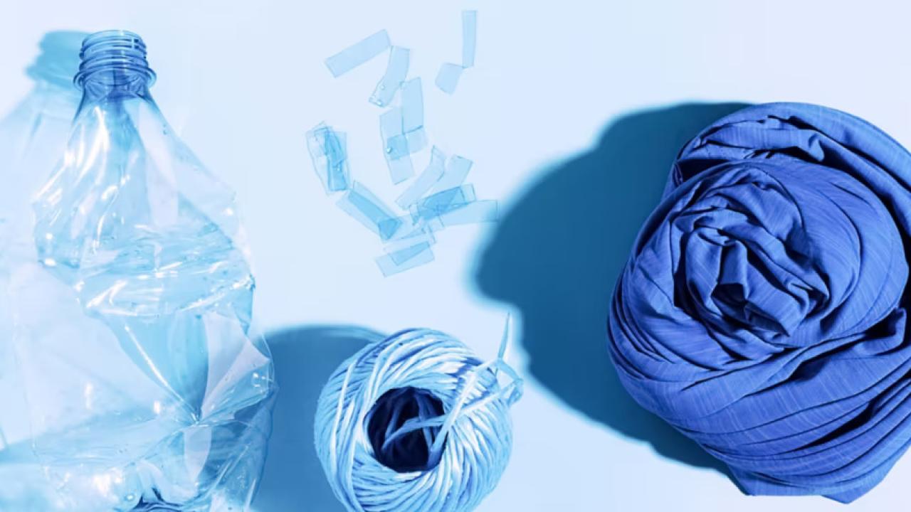 An empty water bottle, spool of thread and piece of fabric all in shades of blue.