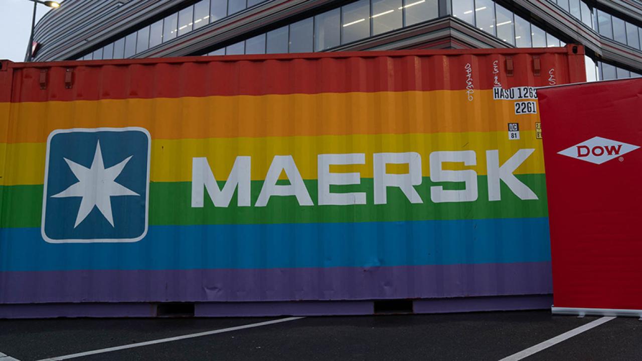 Shipping container painted with rainbow stripes, Maersk and Dow logos on the sides