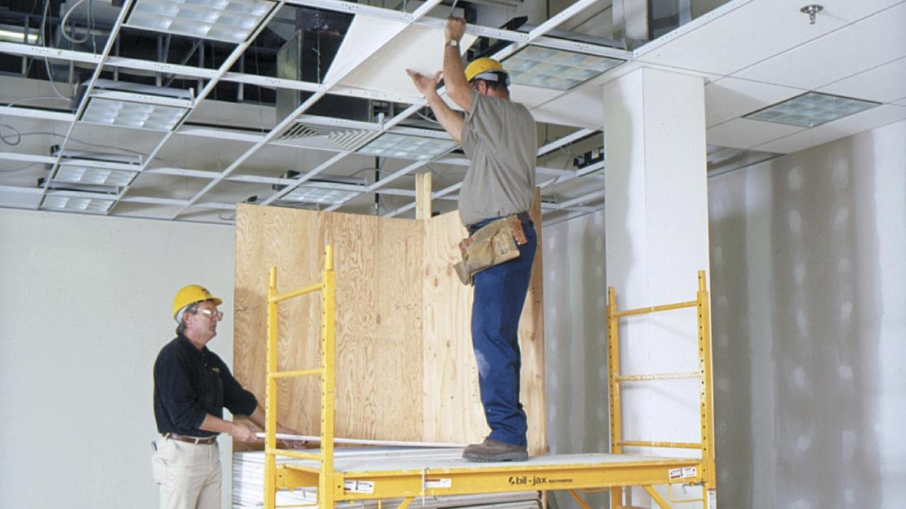 two construction workers putting in a drop ceiling
