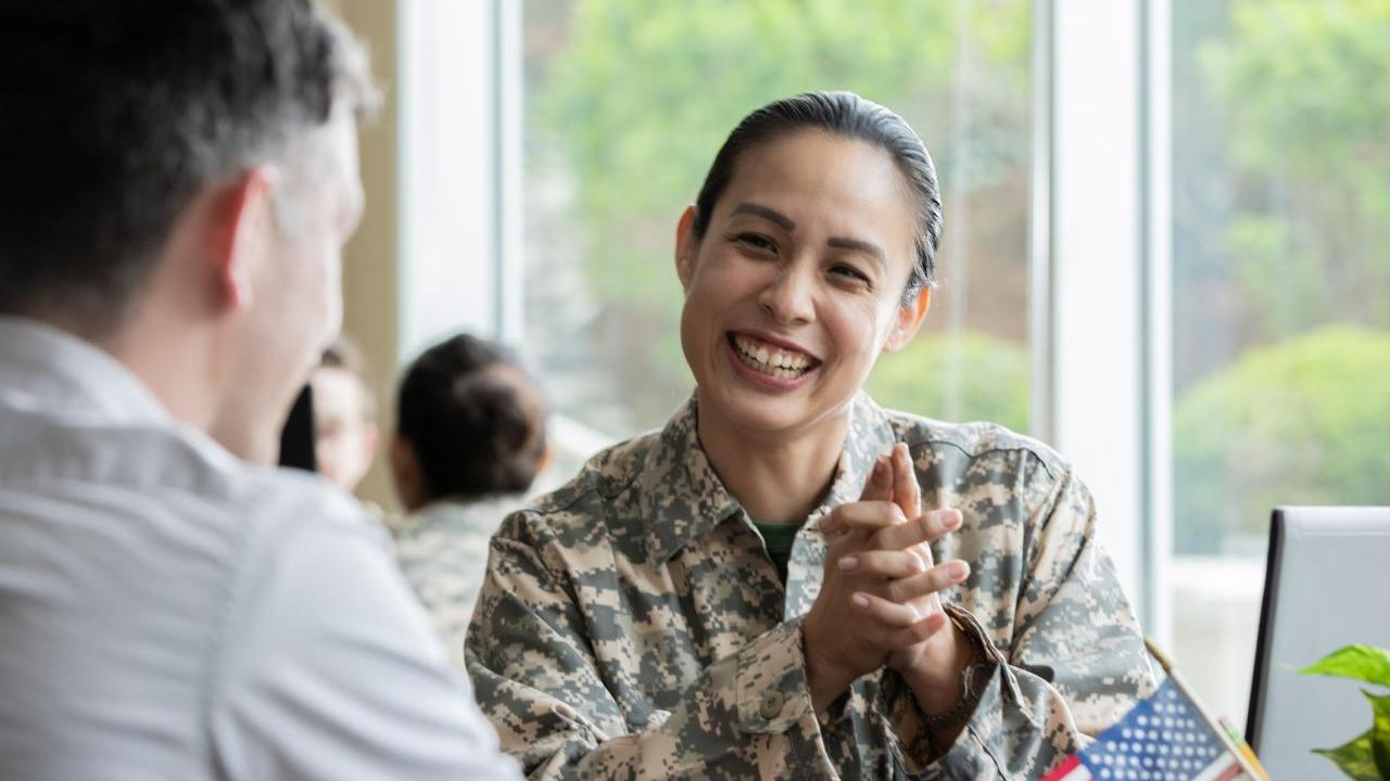 A smiling service member talking with someone
