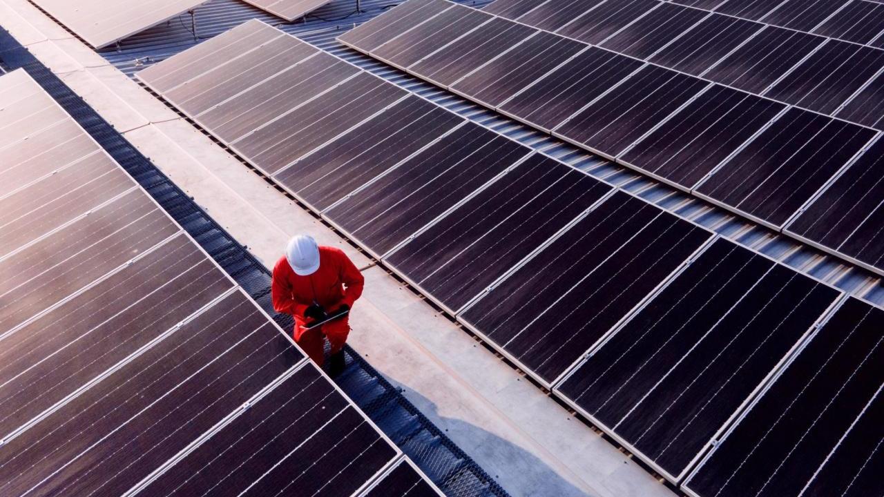 Worker in a hard hat next to solar panels