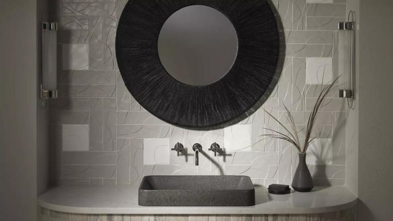 A black and white vanity, sink and mirror. A plant to one side.