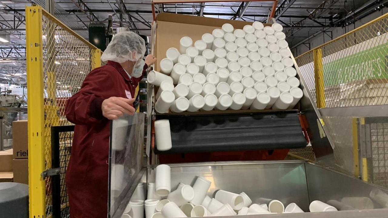 canisters being dumped into a large container in factory
