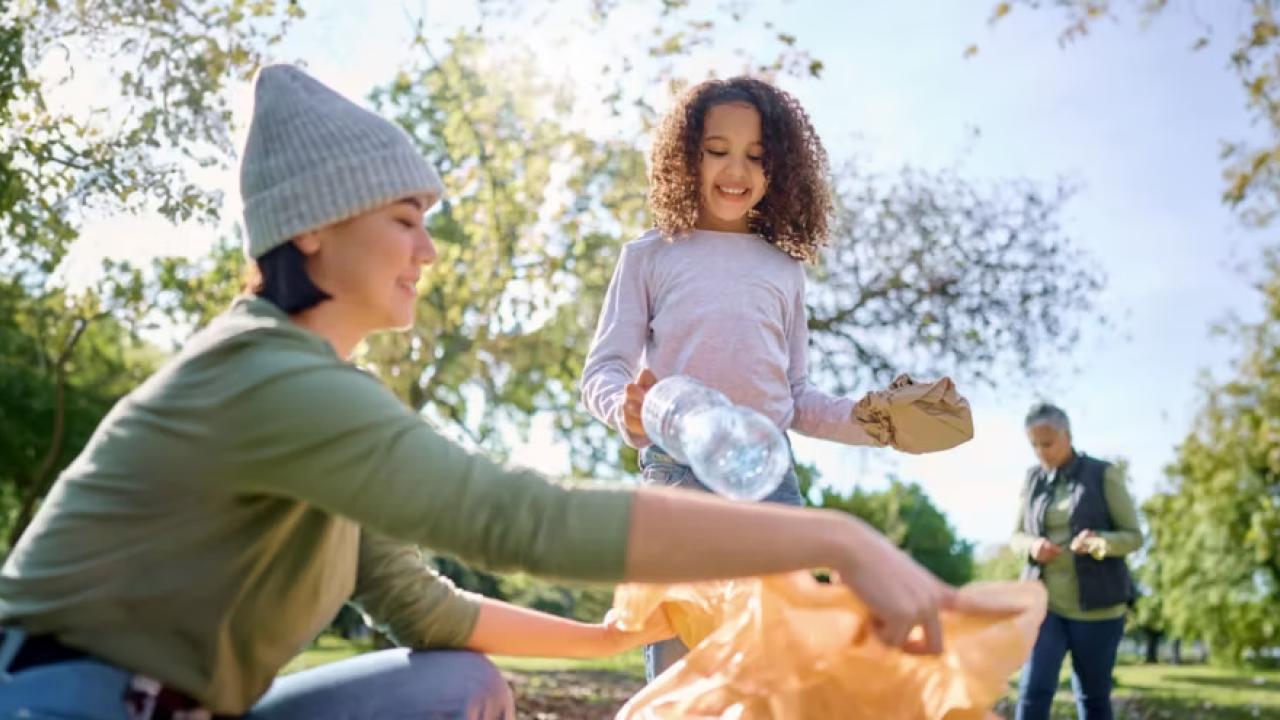 Two adults and a child collecting trash in a park setting.