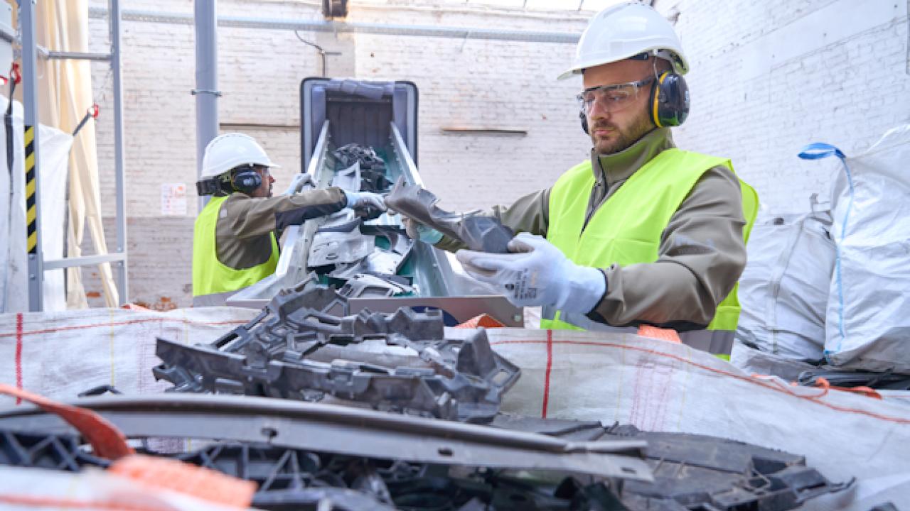 Workers sorting plastics on a conveyor belt.