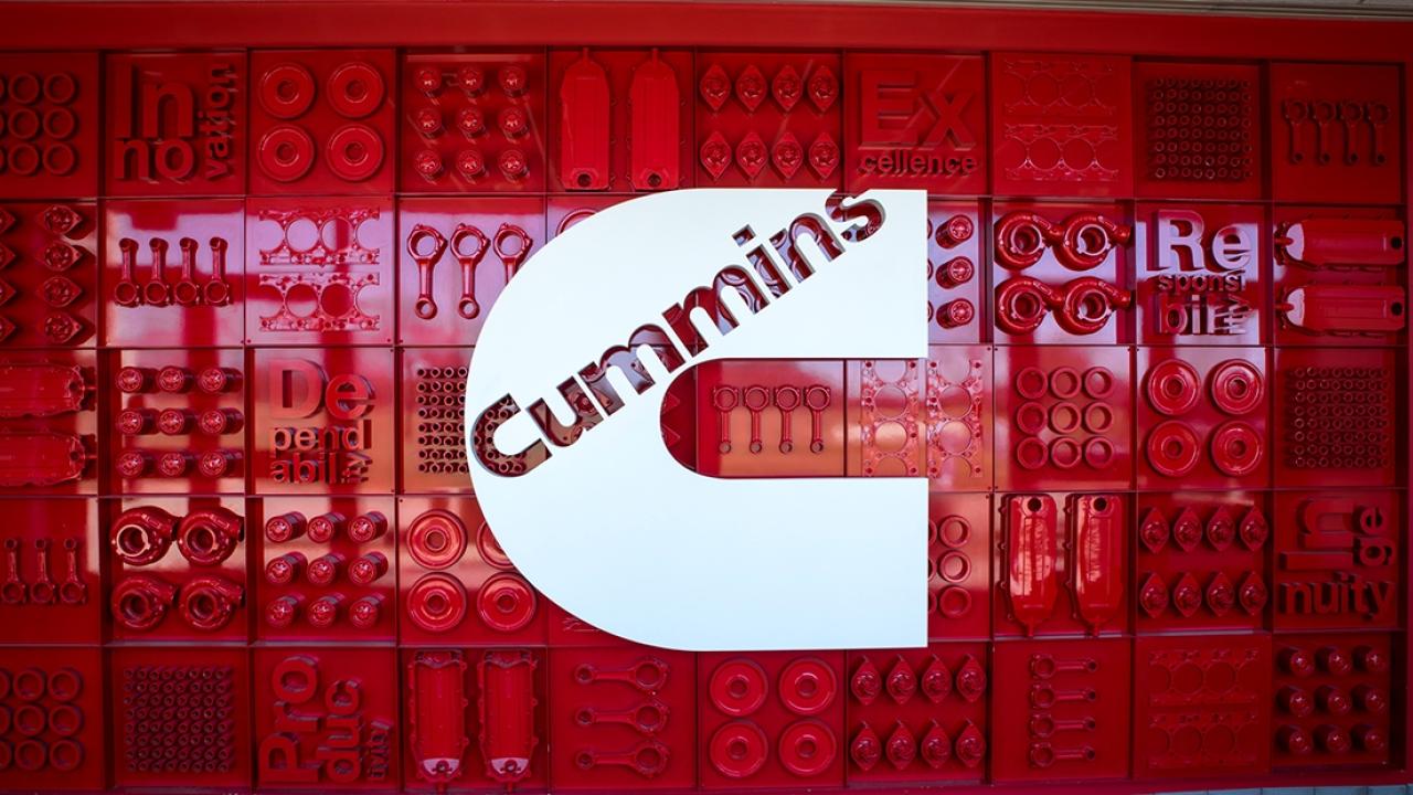 Cummins logo over a red patterned wall.