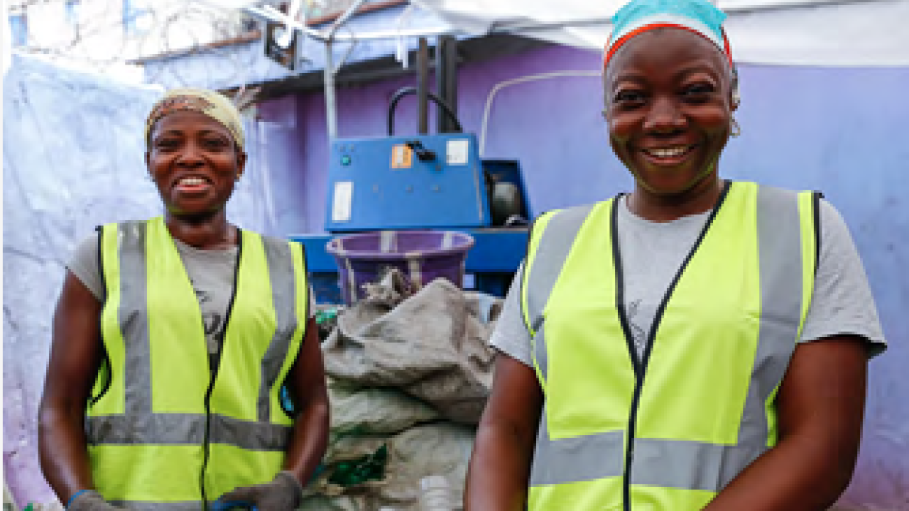 Two people in high-vis vests and hair protection smile at the camera.