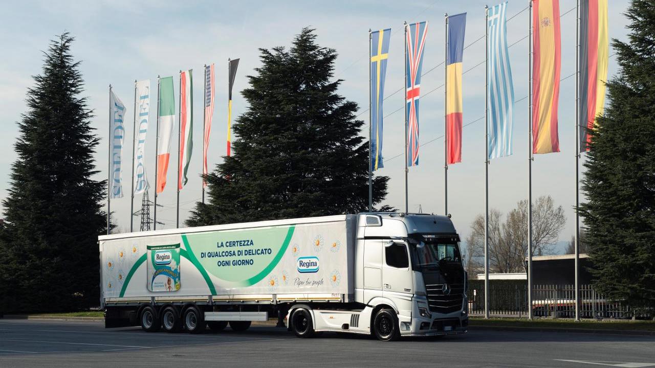 A semi trailer with Regina product picture on the side parked by a row of international flags outside.