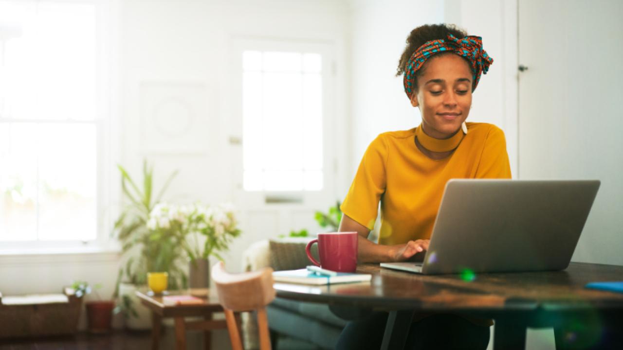 A person in a home setting looking at a laptop.