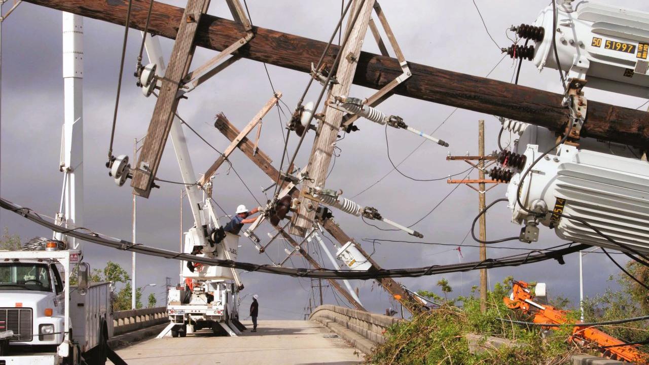 Downed power poles, with Entergy vehicles at work