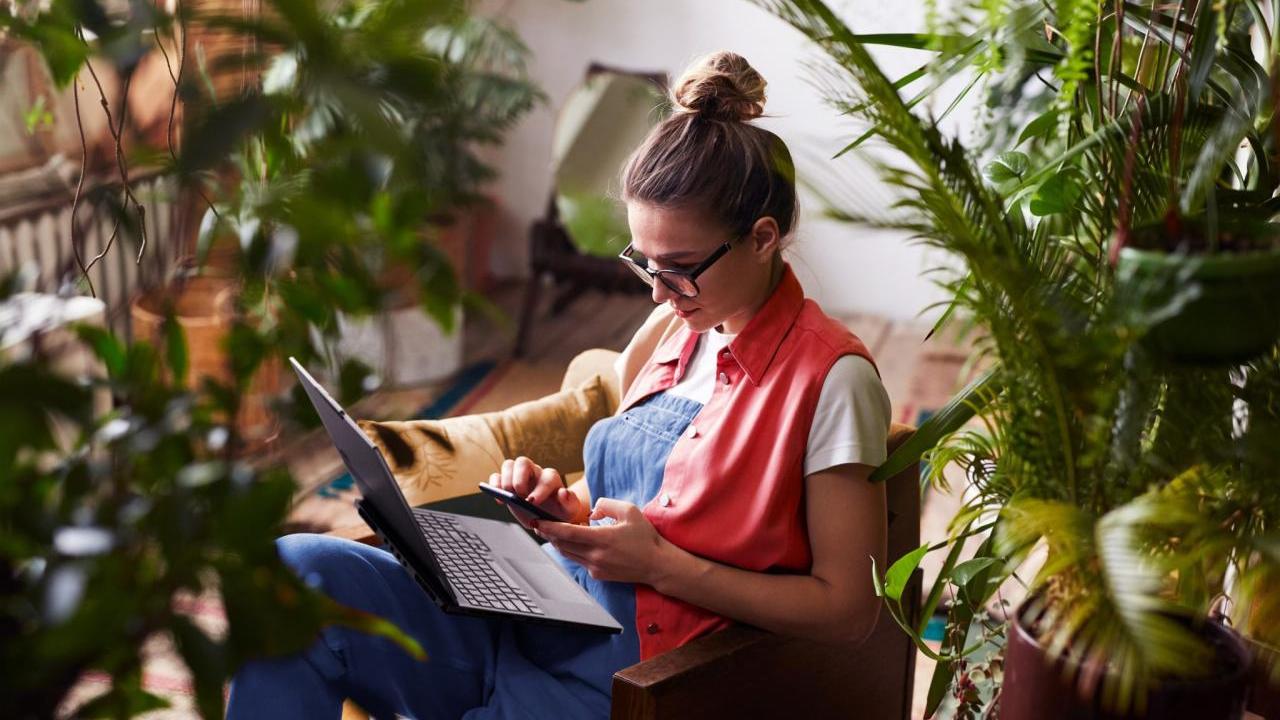 Woman working on laptop surrounded by houseplants