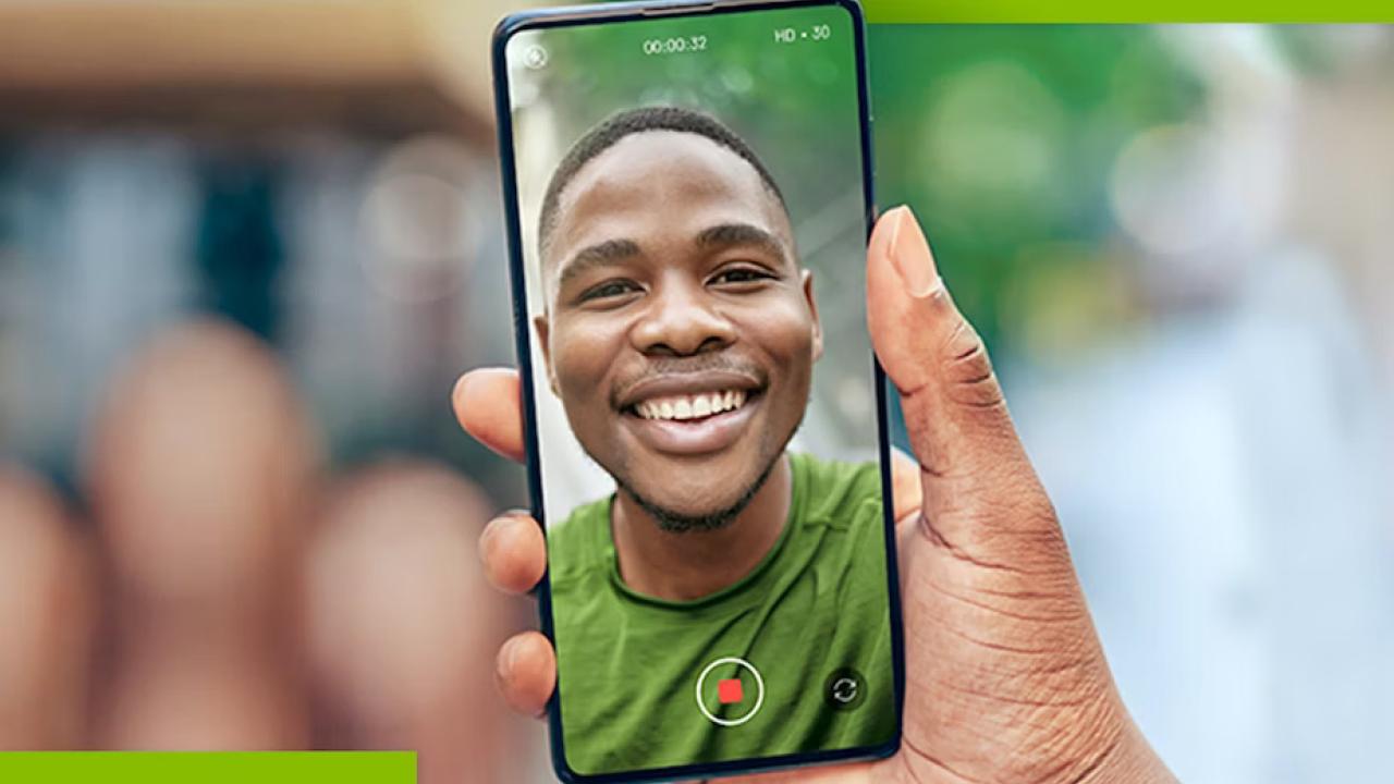A person holding a cell phone with a smiling person displayed.