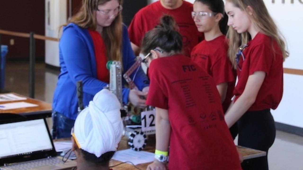 A group of youth and adults working on a robot.
