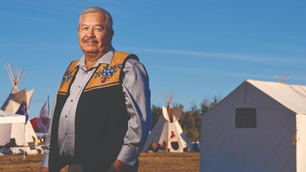 Ron Javier, indigenous buildings in the background.
