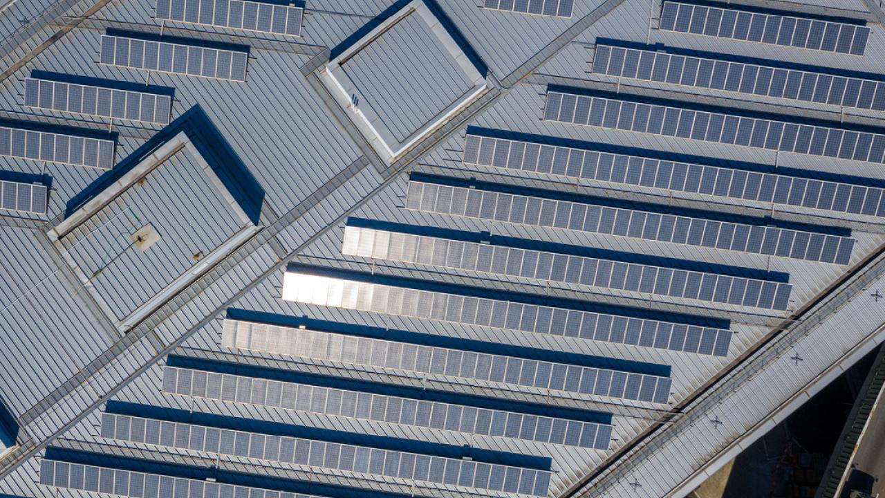 Aerial view of large rows of solar panels on a rooftop.