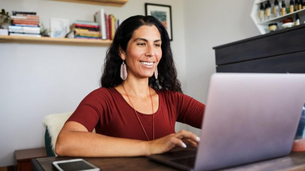 Woman sitting in front of laptop smiling