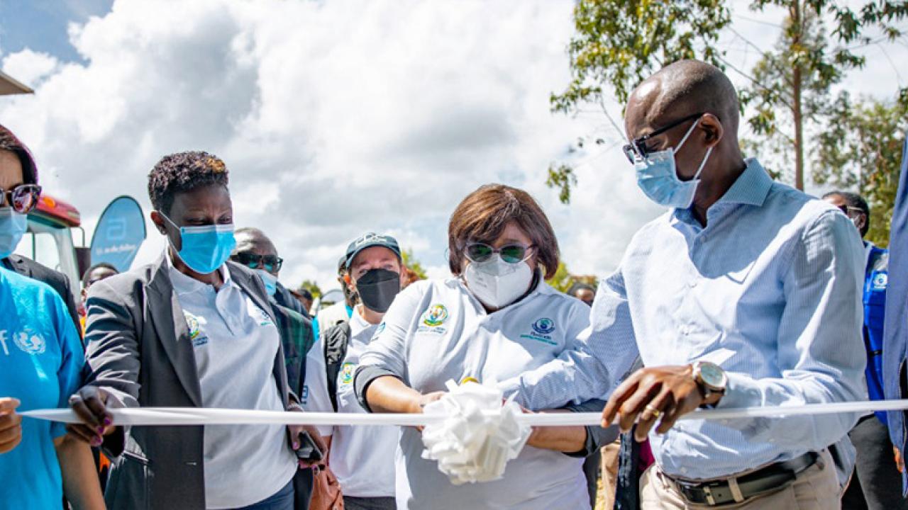 a group of people cut a white ribbon, all wearing medical masks