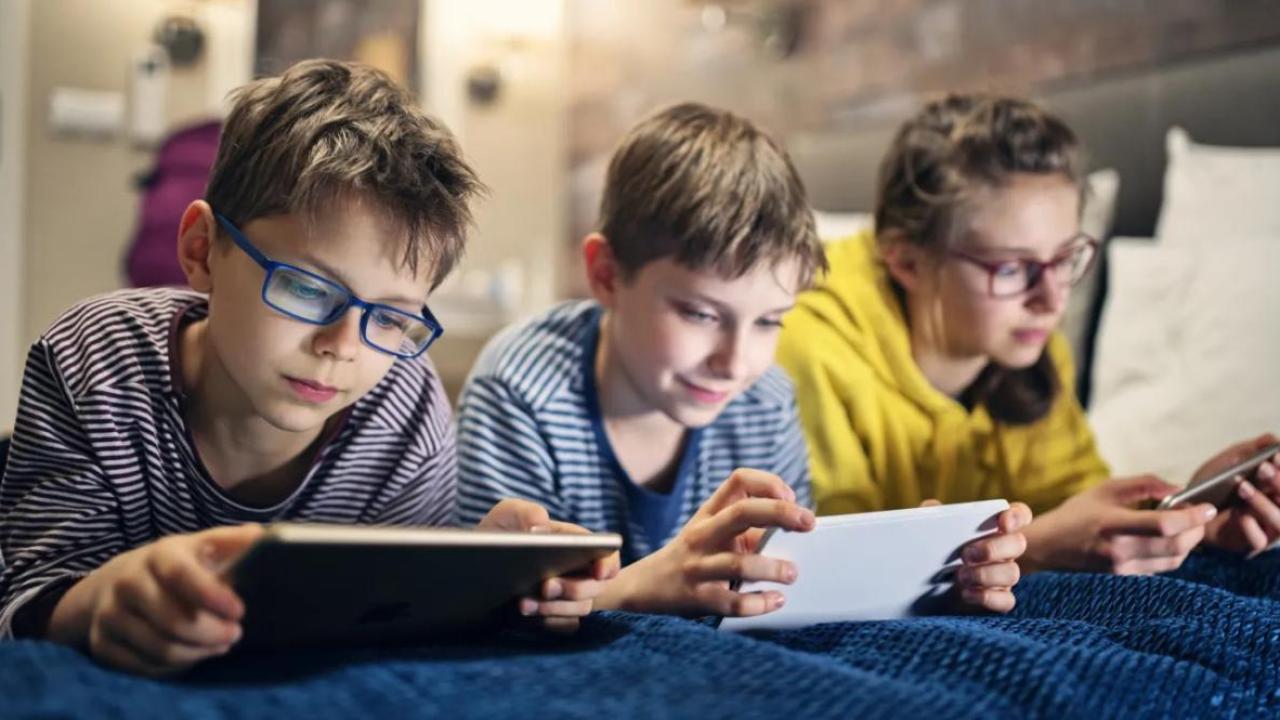 Three children using electronic devices.