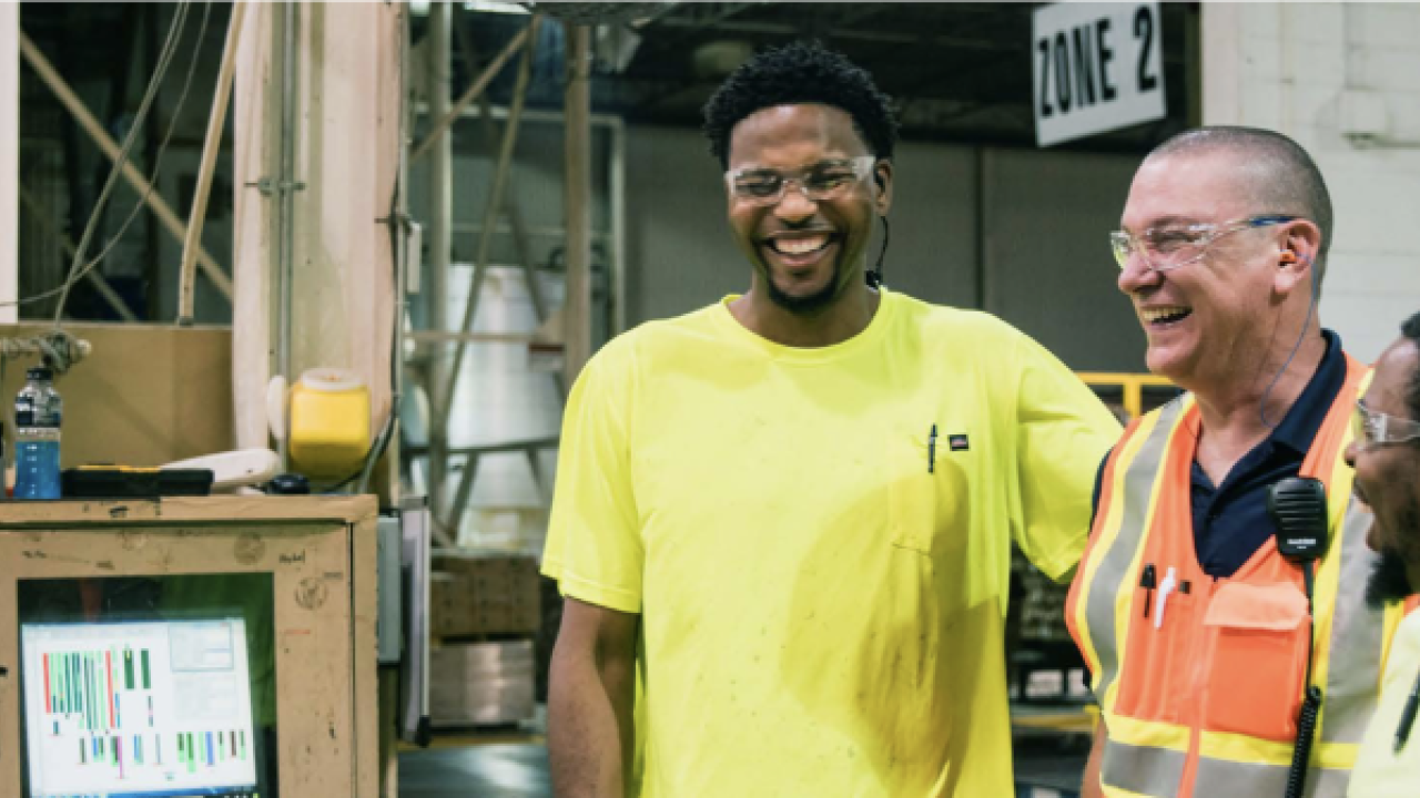 workers in safety gear with arms on each others' shoulders and laughing