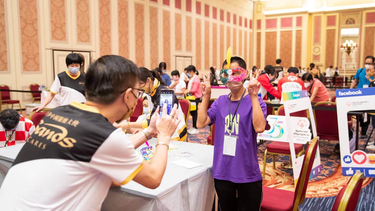 One individual taking a photo of another holding up two peace signs