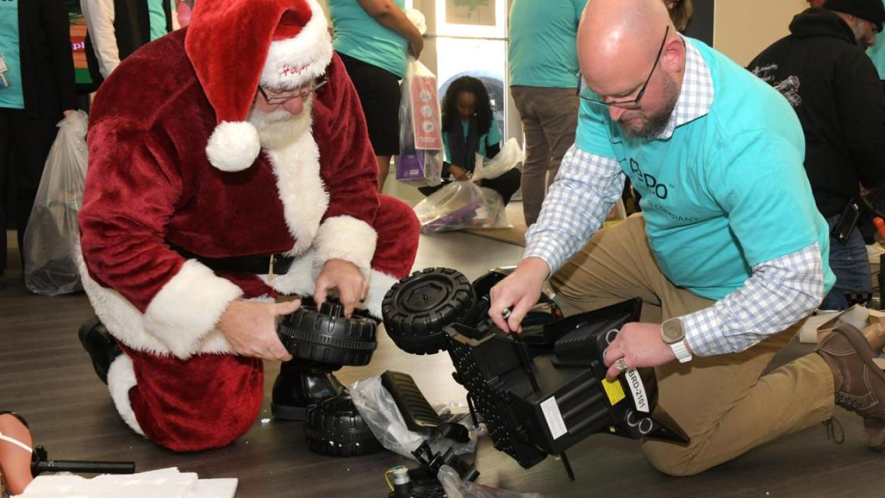 Volunteer helping santa assemble a toy.