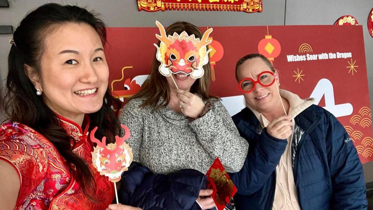 Three people holding up masks