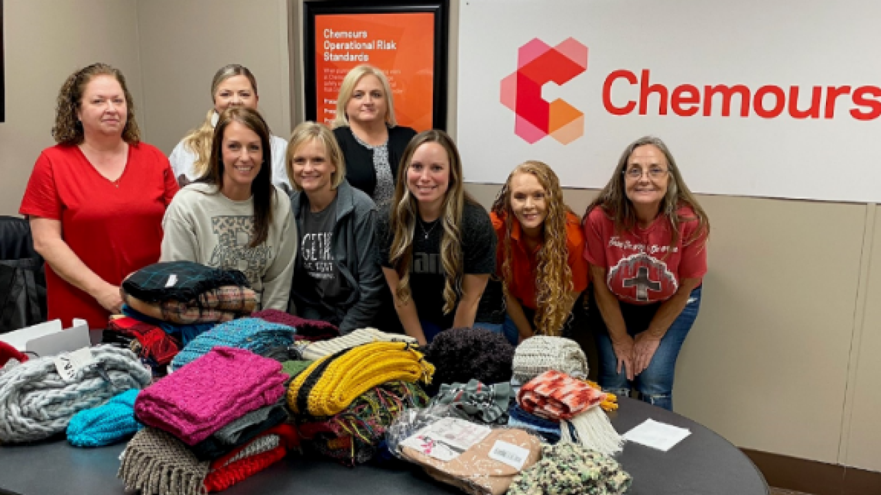 A group of volunteers behind a table full of handmade scarves.