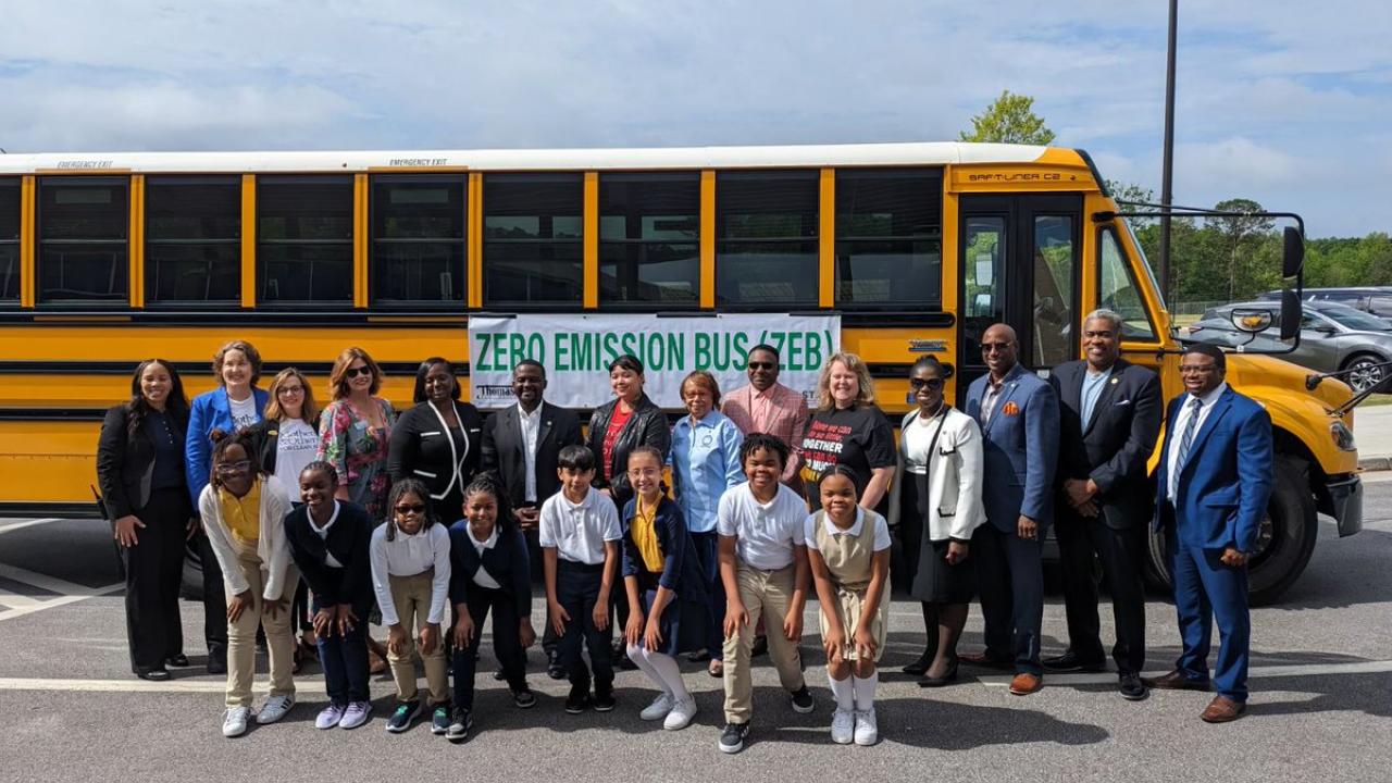 Grantee staff with school officials beside an electric school bus in Clayton County, Georgia