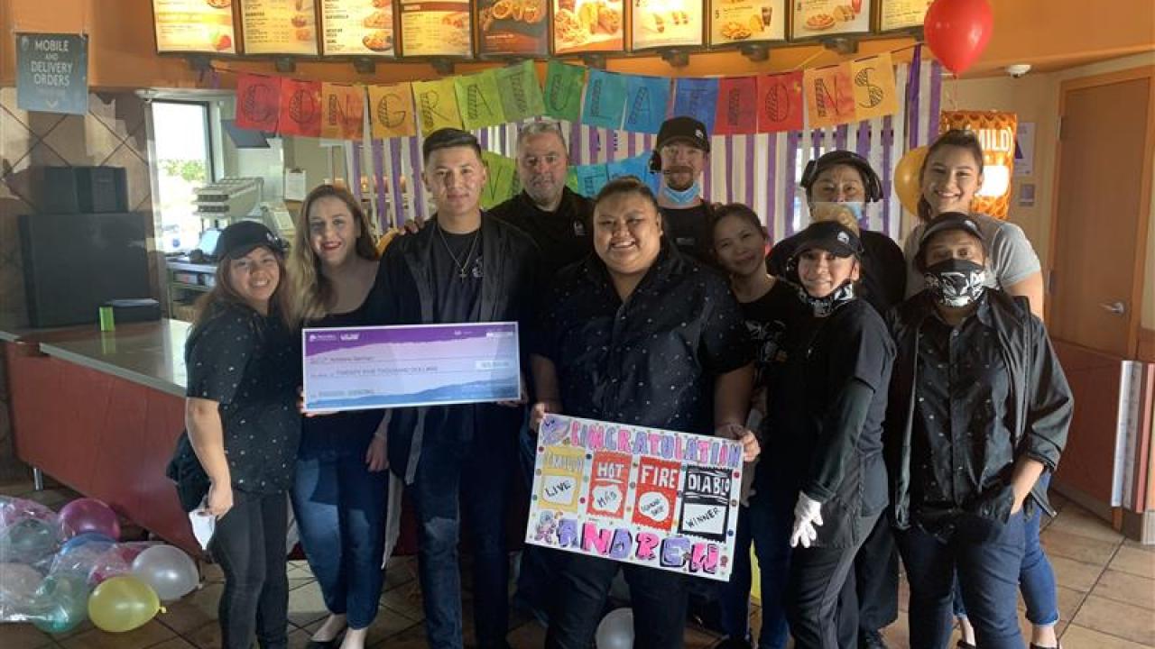 Andrew German with his work crew, holding an oversized check