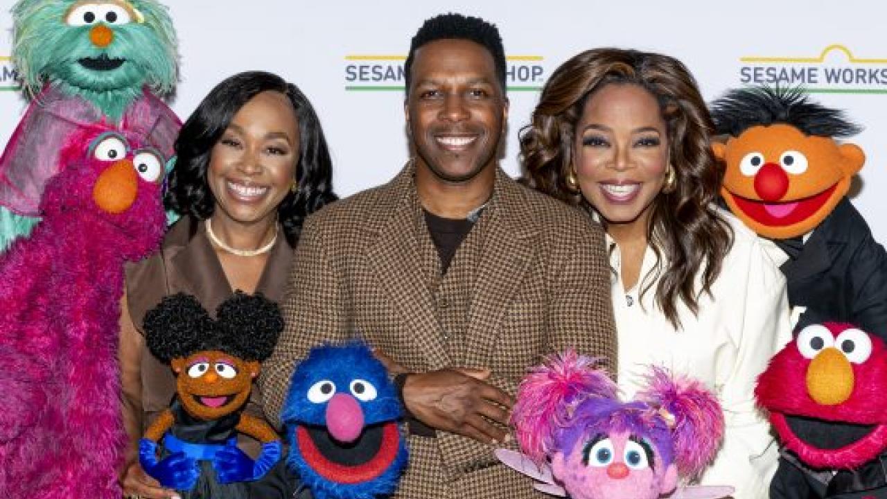 Three people and muppets posed together.