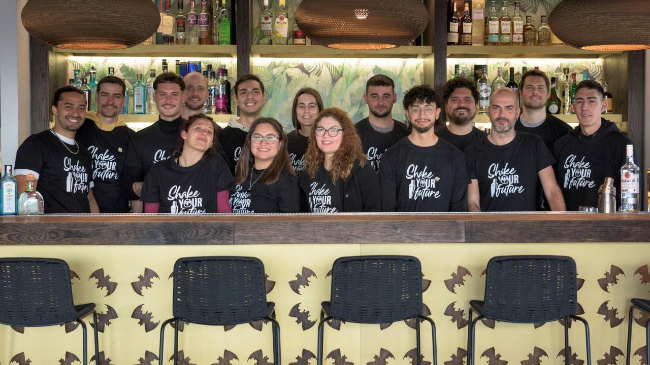 A group of people behind a bar. All wearing matching "Shake your future" t-shirts.