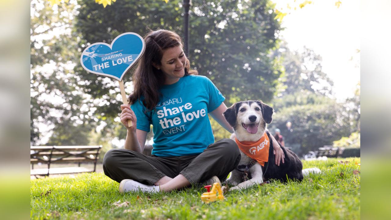 Person wearing "Subaru share the love event" shirt sitting next to a dog