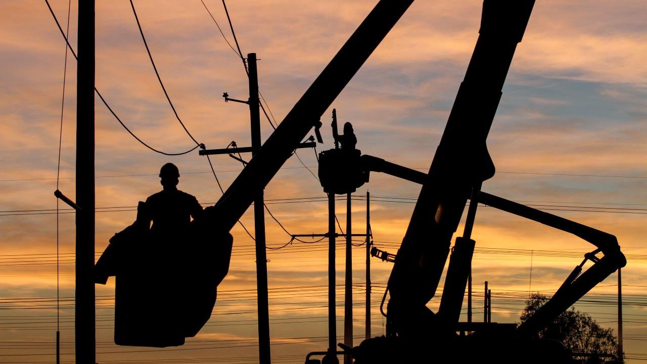 silhouette of someone working on a powerline