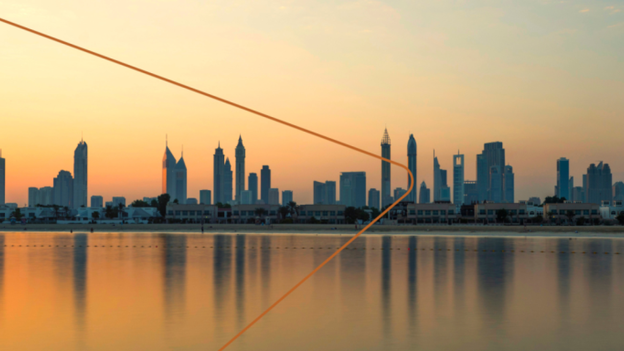 A city skyline at sunset, a body of water in front.