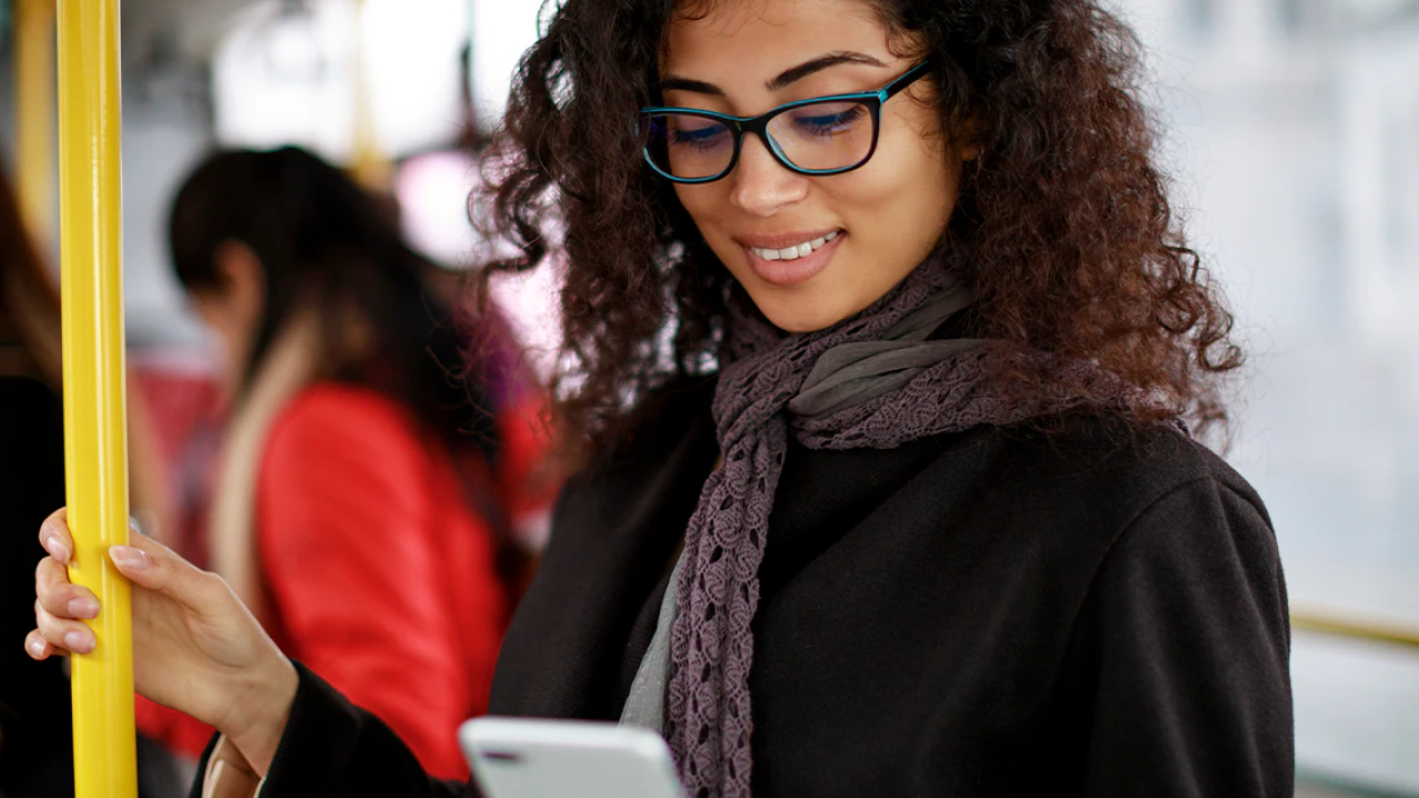 smiling woman on her phone on public transportation