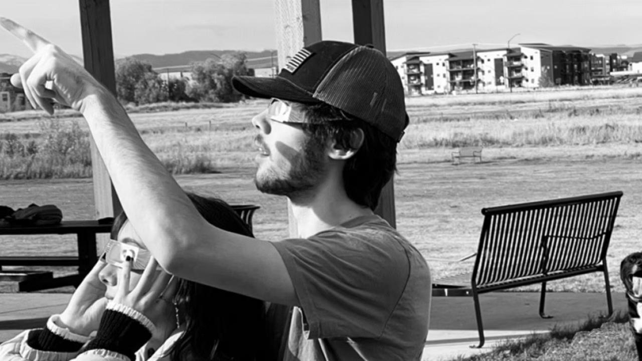 A black and white photo of two people watching an eclipse.
