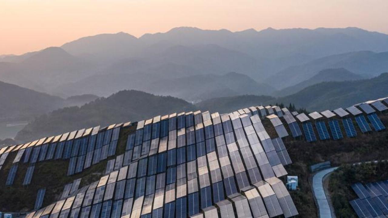 Aerial view of a hilly landscape covered in solar panels.