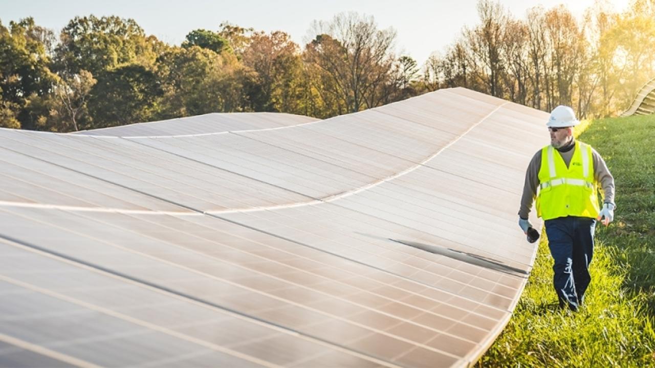 a person in safety gear walking alongside solar panels