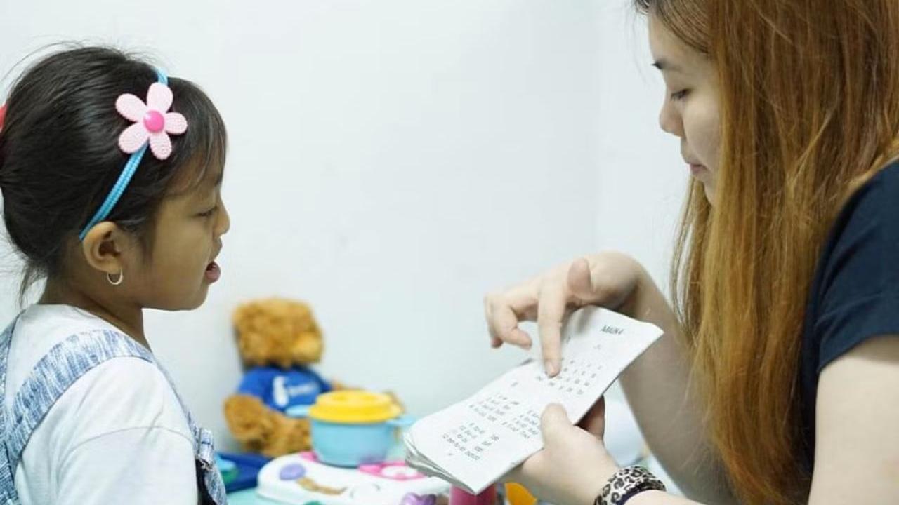 A caregiver works one-on-one with a young child during a speech therapy session.
