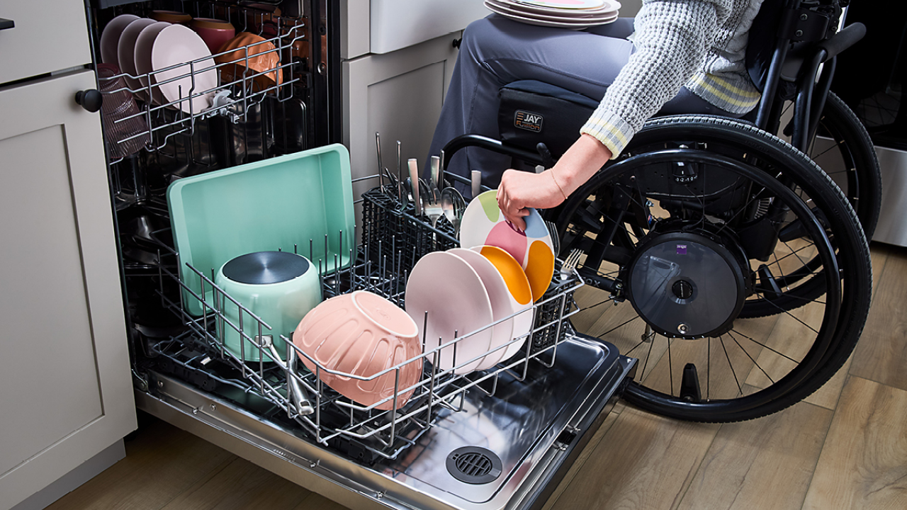 A person in a wheelchair unloading a dishwasher