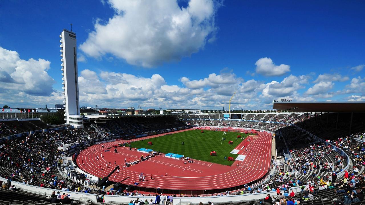aerial view of a large stadium filled with spectators, a blue sky with few clouds
