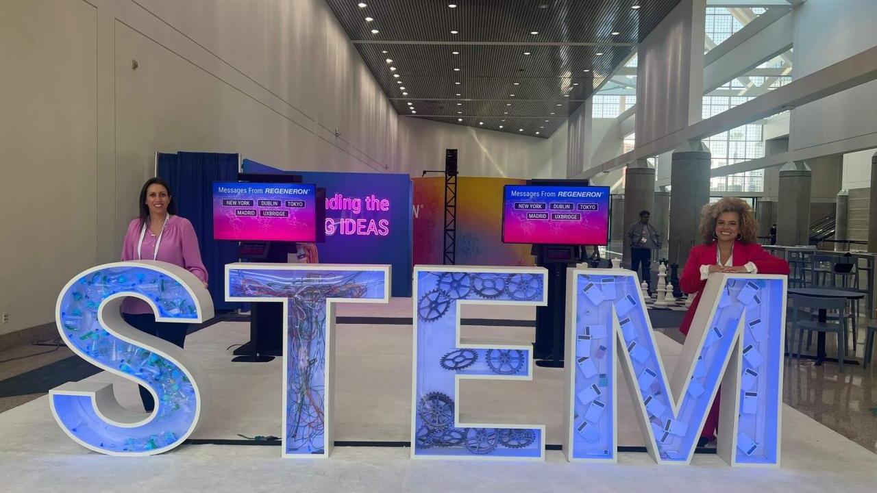 Two people standing behind large letters "S T E M".