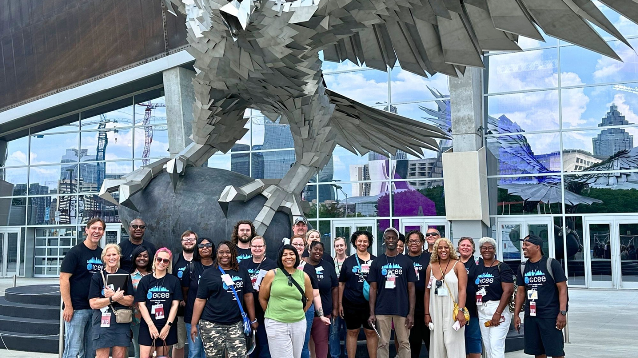 A smiling group posing in front of an eagle sculpture