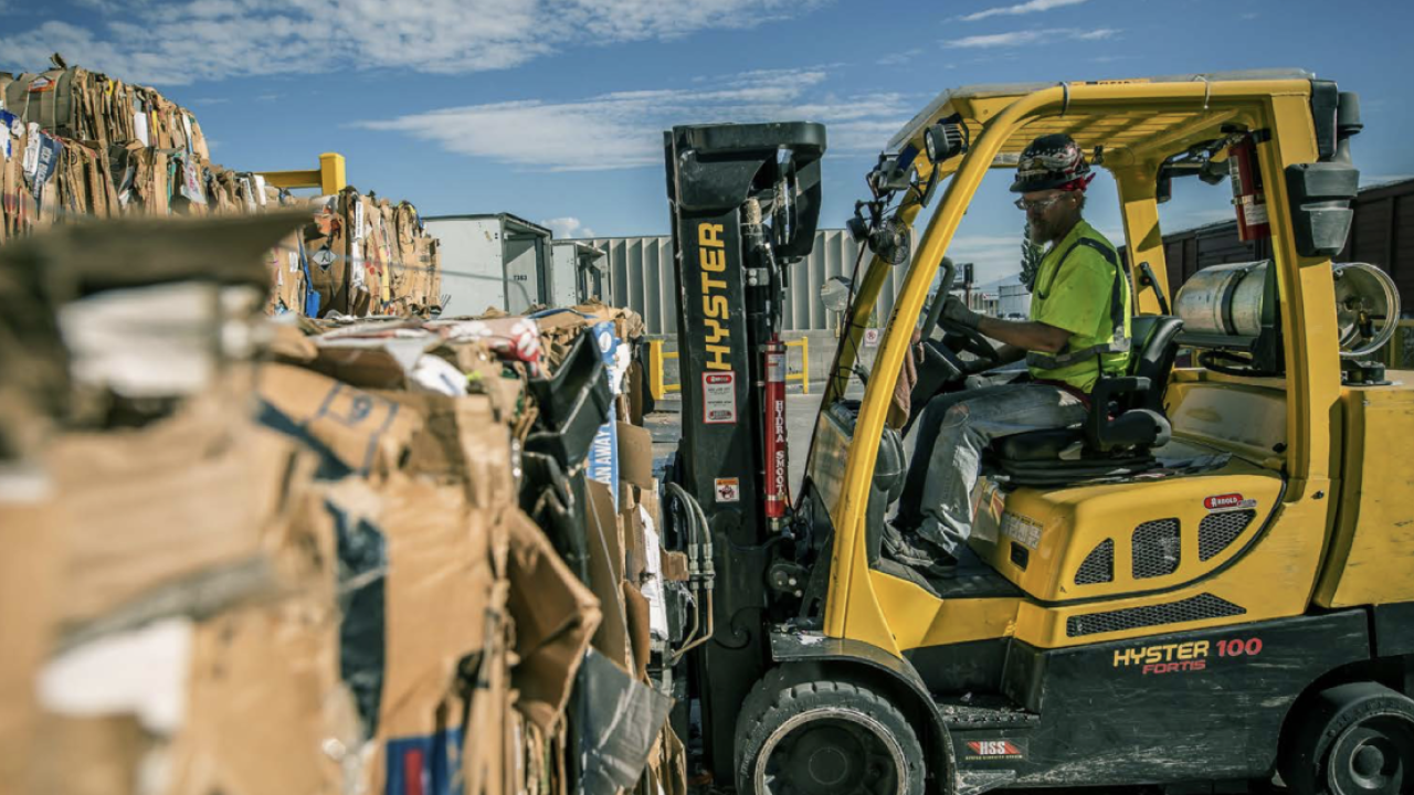 forklift working in an outdoor field of recovered cardboard