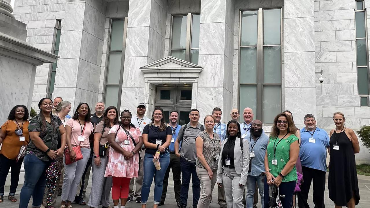 a large group outside a stone block building