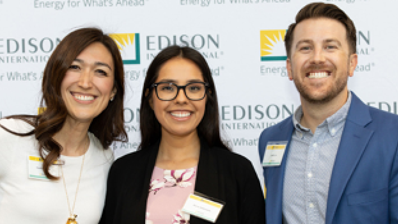 Three people posed in front of an Edison backdrop.