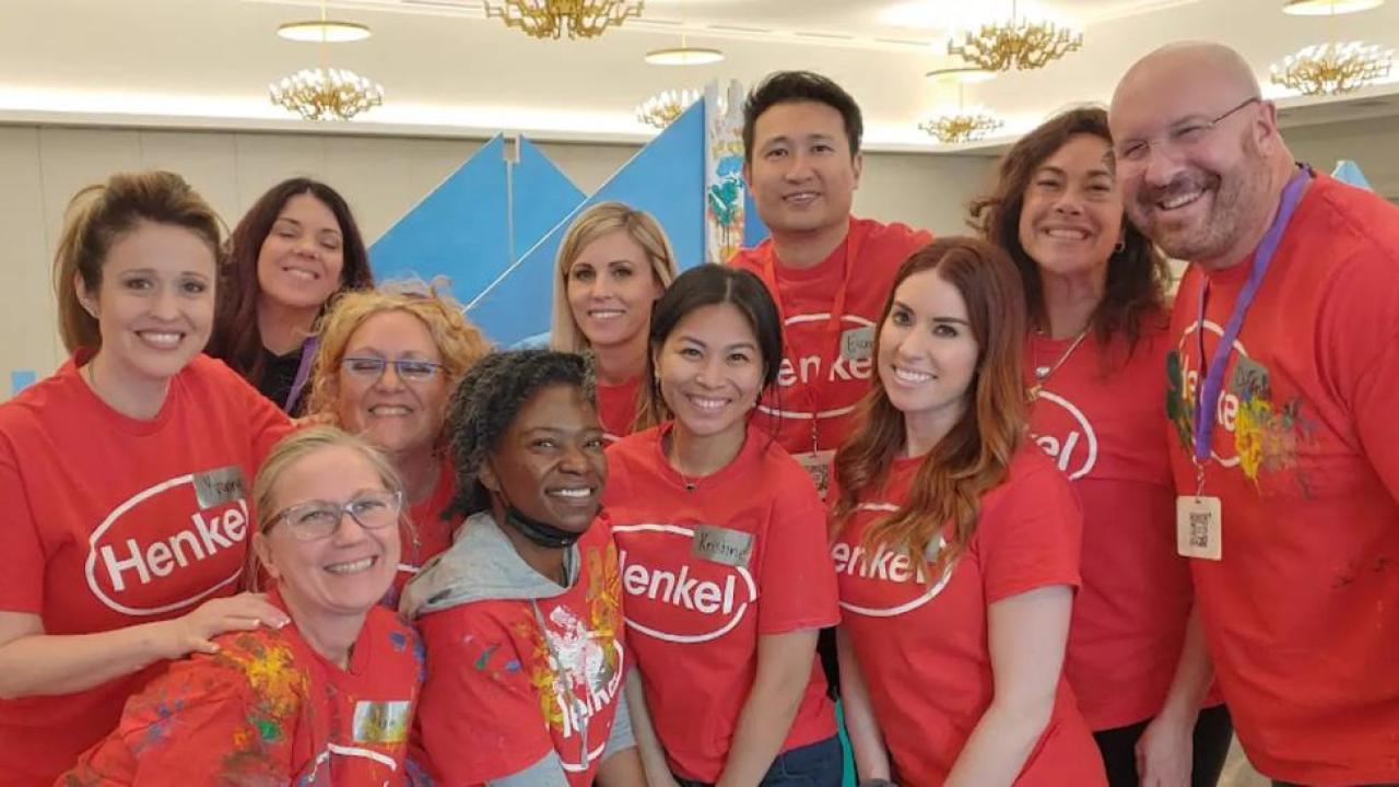 A group of people huddled for the photo. Wearing matching Henkel t-shirts.