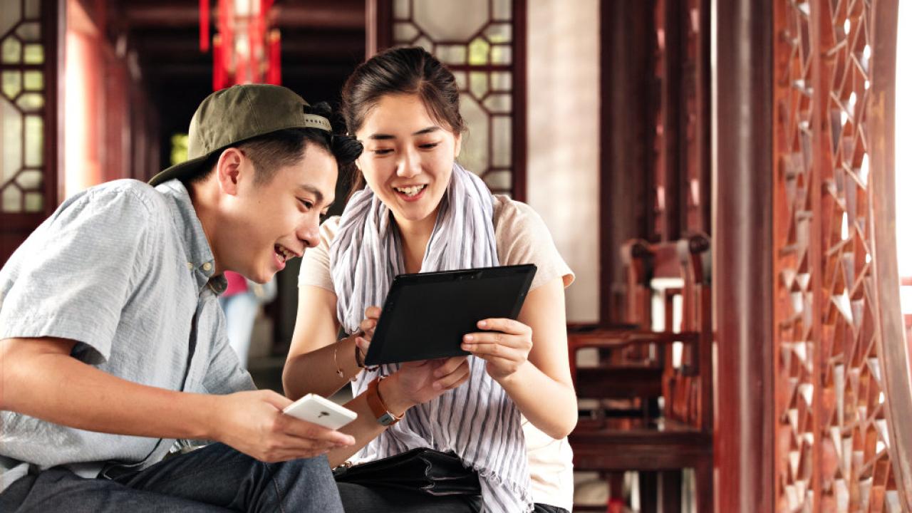 Two people looking at a handheld device indoors.
