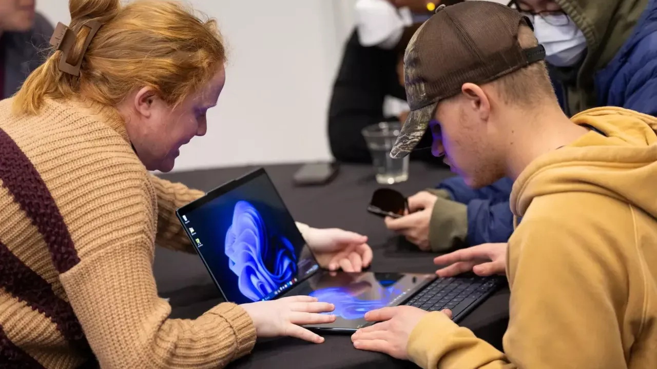 Two people working with an open laptop.